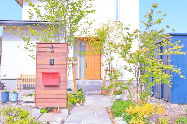 緑豊かな植栽と石畳のアプローチが美しい、赤いポストのある住宅の玄関